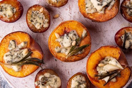Grilled baked peach and plums stuffed with blue cheese dorblu and rosemary. Top viewの写真素材
