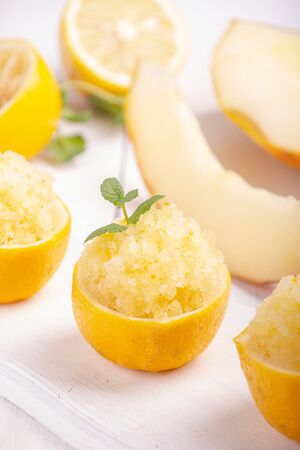 Melon and lemon fruit sorbet. Summer refreshing dessert in half of lemon fruit peel over on white background.の写真素材