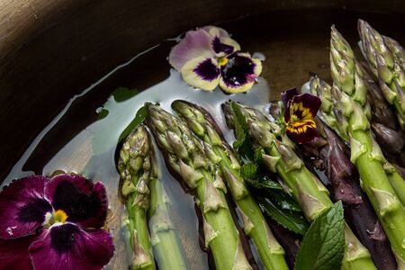Set of raw white, green, purple asparagus in copper basin with violet and mint. Old wooden rustic background. Organic healthy eating concept. Overhead.の写真素材