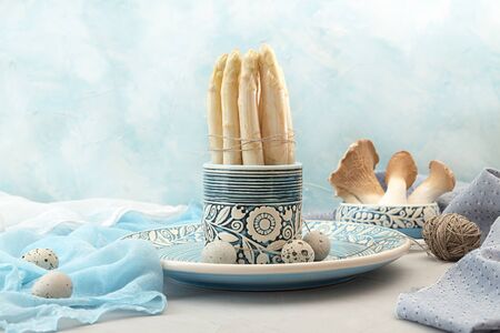 Still life with organic white asparagus, oyster mushrooms, garlic and quail eggs against blue background. Healthy dieting food concept.の写真素材