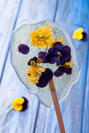 Beautiful lollipop caramel with edible violet flowers on dark blue background.の写真素材