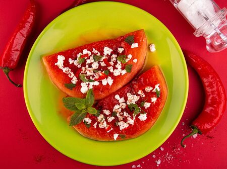Grilled watermelon with feta cheese, chili pepper and min on green plate on red background. BBQ healthy food concept. ÐµÑÐ· Ð¼ÑÑÑの写真素材