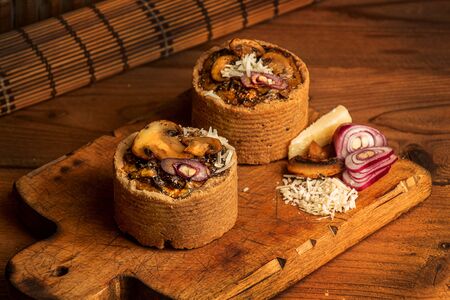 Tarts with mushrooms, caramelized red onion and cheese over on old wooden rustic background.の写真素材