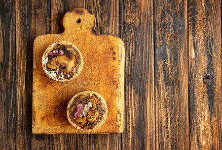 Tarts with mushrooms, caramelized red onion and cheese over on old wooden rustic background. top view, copy spaceの写真素材