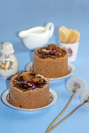 Tarts with mushrooms, caramelized red onion and cheese over on blue backgroundの写真素材