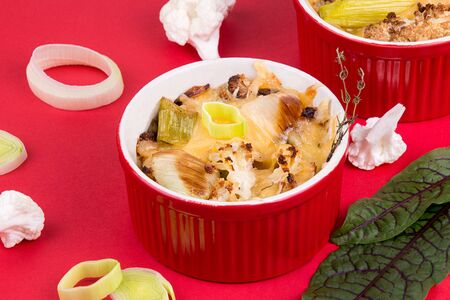 Cauliflower gratin with leek, chicken breast and cheese on red backgrouns.の写真素材