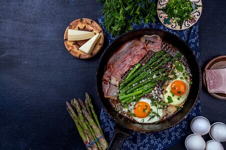 Delicious breakfast lunch branch of fried eggs, bacon, green asparagus, greenery and parmesan cheese on pan. top view, copy spaceの写真素材