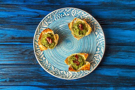 Tarts with cottage cheese, spinach, egg, mushrooms, garlic and bacon on blue plate over on blue wooden background. Top view overheadの写真素材