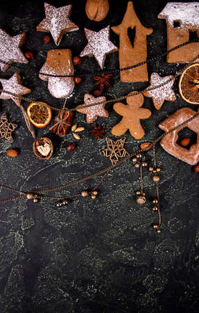 Greeting card with decor gingerbread cookies, dried orange fruit slices, Christmas and New Year ornament on black concrete background. Overhead of Christmas New Year holiday background. Top view. Copy spaceの写真素材