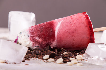 Strawberry ice cream lolly pops with whipped cream decorated chocolate and ice cubes on white wooden background. Close upの写真素材