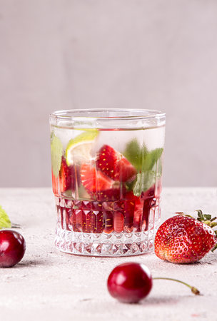 Summer strawberry sweet cherry cocktail ice cold drink in glasses on gray background. Copy spaceの写真素材