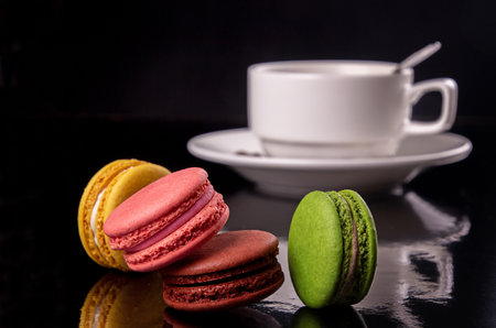 colorful macarons and cup of coffee over on black background.の写真素材