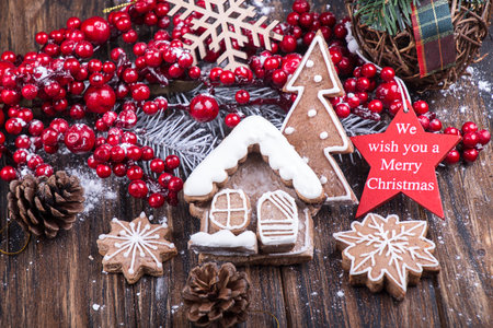 Christmas New Year decorations. Holly berries, sweet Christmas gingerbread cookies in shape of house...
