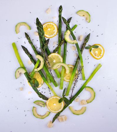 Flat lay composition set of blanched green asparagus, lemon and avocado slices, mint leaves and...
