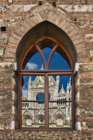 The Duomo (Cathedral) of Siena reflecting in gothic window, Tuscany, Italyの写真素材