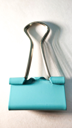 One turquoise paper clip close up on a white backgroundの写真素材