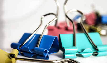 Multicolored paper clips in a pile closeup on a white backgroundの写真素材
