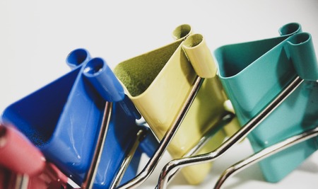 Multicolored paper clips in a pile closeup on a white backgroundの写真素材
