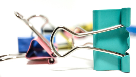 Multicolored paper clips in a pile closeup on a white backgroundの写真素材