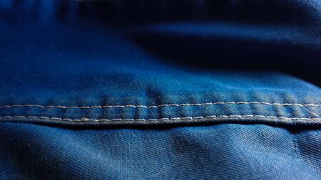 Close-up old work uniform with scuffs on a lowercase seam of blue denimの写真素材