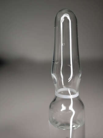 One glass ampoule on light white background close up