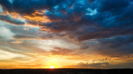 Beautiful sunset over the field and forest. The sun is reflected in the clouds. View from above. Ural Russia 2021.の写真素材