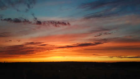 Beautiful sunset over the field and forest. The sun is reflected in the clouds. View from above. Ural Russia 2021.の写真素材