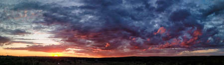Beautiful sunset over the field and forest. The sun is reflected in the clouds. View from above....