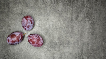Three fresh plums on gray marble background.の写真素材