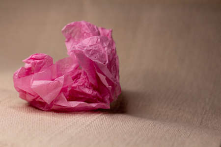 Pink heart made of crumpled paper on a light background close-upの写真素材