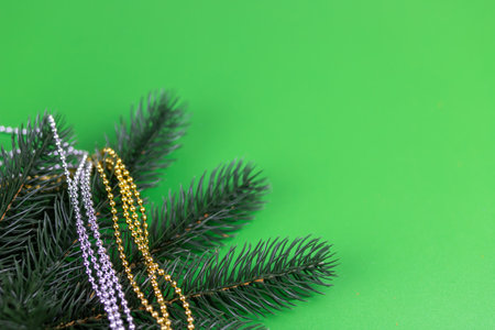 Christmas composition of spruce branches and gold and silver beads on a green background.の写真素材