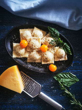 Ravioli with cheese and cherry tomatoes on a black plate.の写真素材