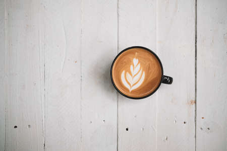 Latte art coffee on wooden table in coffee shopの写真素材