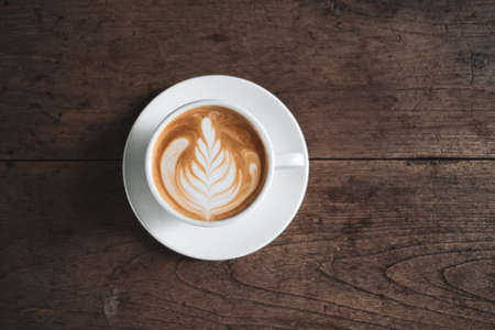 Latte art coffee on wooden table in coffee shopの写真素材