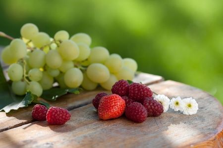 Grapes, strawberries and raspberries on wood table