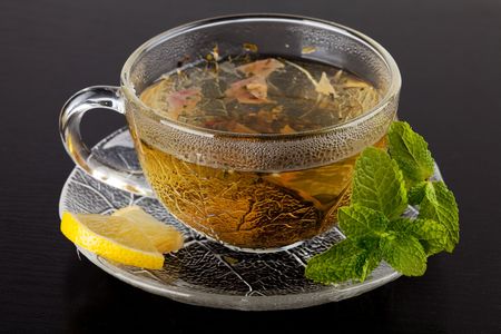 Cup of green tea with lemon and mint on dark wood tableの写真素材