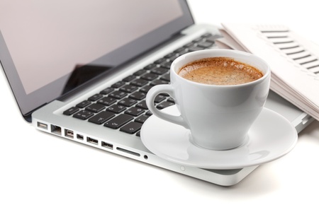 Hot cappuccino cup on laptop and newspaper. On whiteの写真素材