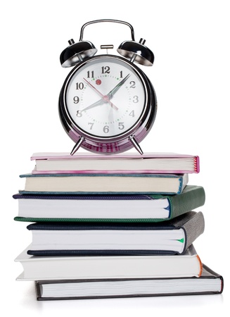 Alarm clock on notepads and books. Isolated on white backgroundの写真素材
