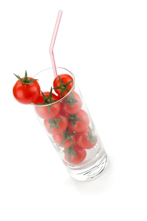 Cherry tomatoes in glass with drinking straw. Isolated on white backgroundの写真素材
