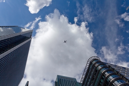 The sky with airplane surrounded by office skyscrapersの写真素材