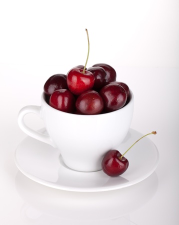 Ripe cherries in a coffee cup. On whiteの写真素材