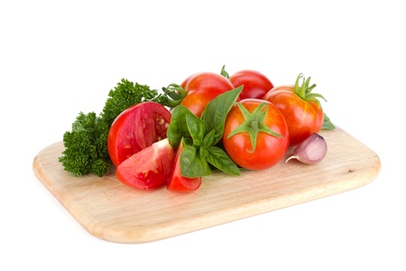 Ripe tomatoes, basil and parsley on cutting board. Isolated on white backgroundの写真素材
