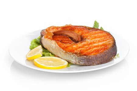 Grilled salmon with lemon slices and herbs on plate. Isolated on white backgroundの写真素材