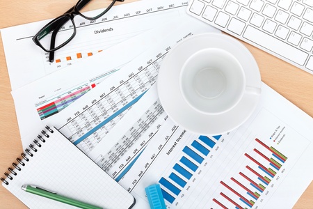 Empty cup on contemporary workplace with financial papers and office supplies