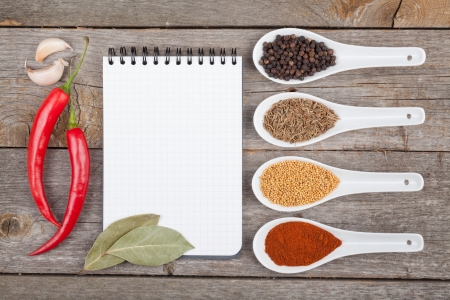 Colorful herbs and spices selection. Aromatic ingredients on wood table with blank notepad copyspaceの写真素材