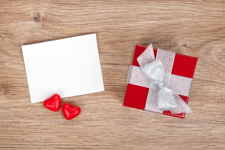 Blank valentines greeting card and small red gift box on wooden backgroundの写真素材