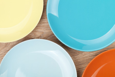 Colorful plates and saucers over wooden table background. の写真素材