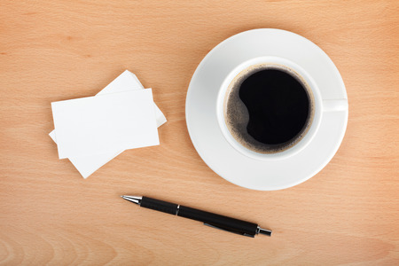 Blank business cards with coffee cup and pen on wooden office tableの写真素材