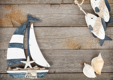 Toy sailboat and fish with seashells on a wooden background with copy spaceの写真素材