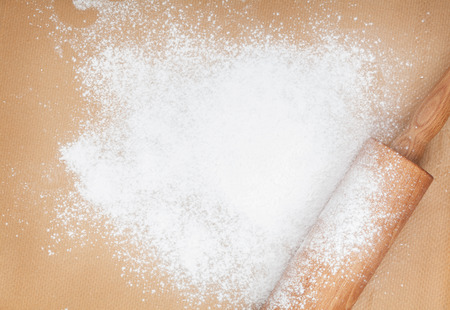 Wooden rolling pin with flour on cooking paperの写真素材